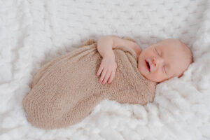Nouveau-né endormi en cocon beige au studio Pierre Lepoutre