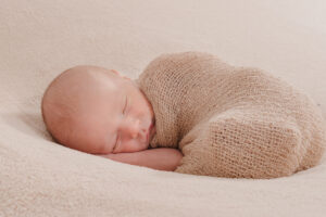 Bébé couché sur le côté, enveloppé dans un tissu tricoté